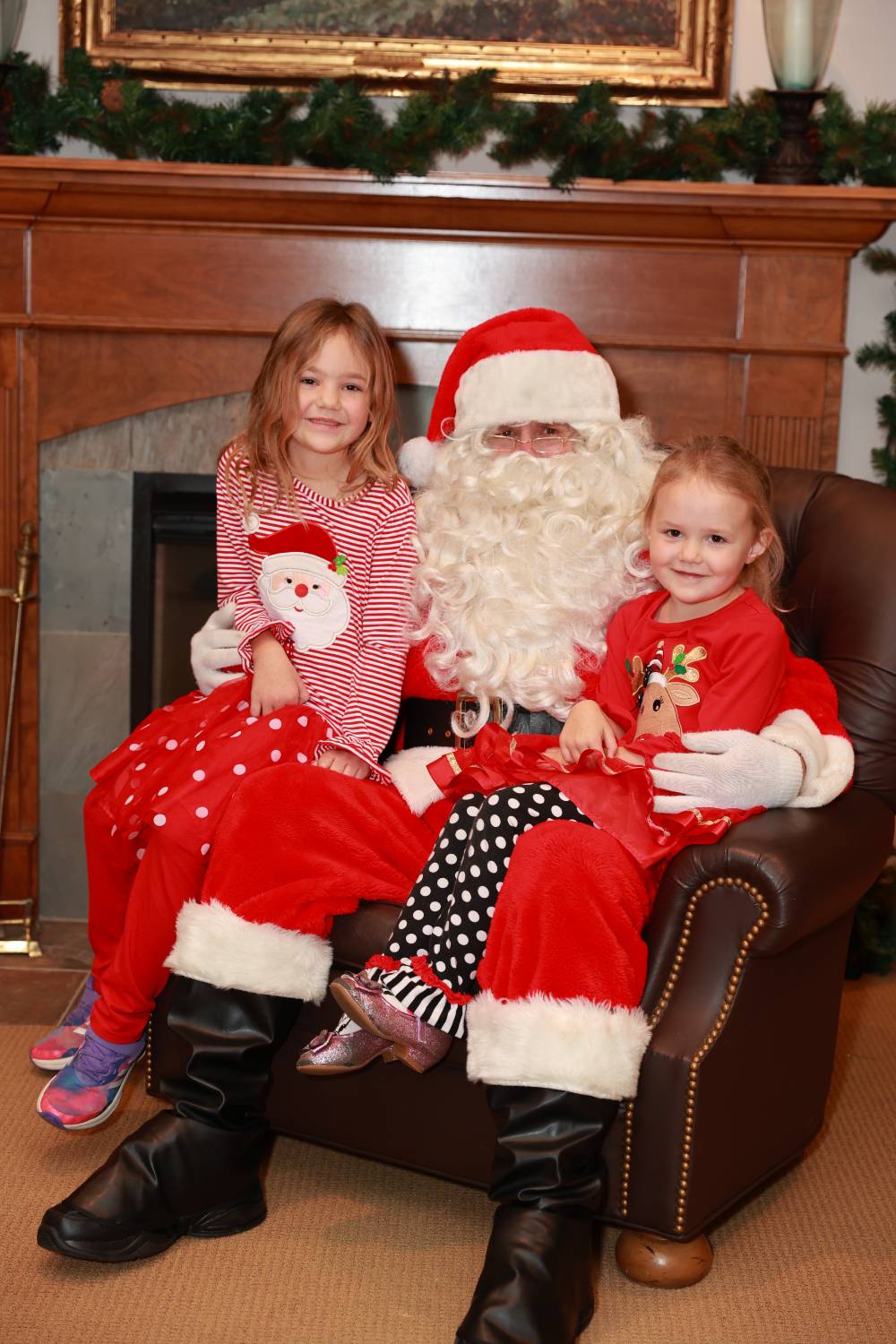 Two daughters of alumni sitting with Santa.